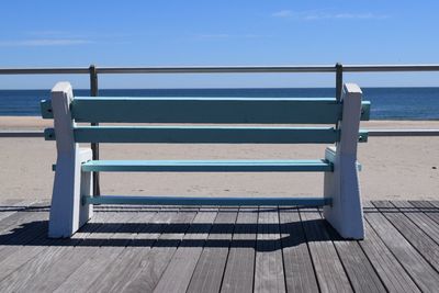 Wooden railing on beach against sky