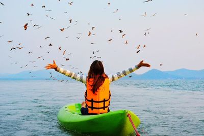 Woman kayaking on sea against sky