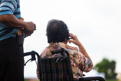 Rear view of man photographing woman against sky