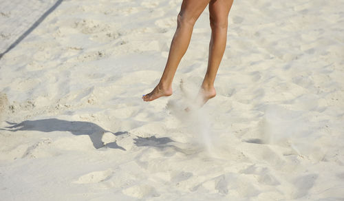 Low section of woman jumping at beach