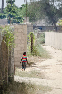 Rear view of boy walking on road