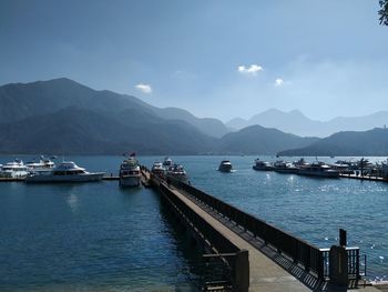 Scenic view of harbor by mountains against sky