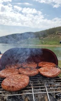 Meat on barbecue grill against sky