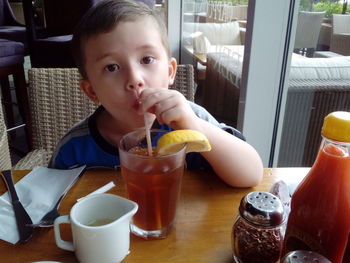 Portrait of boy drinking ice tea in restaurant