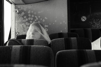 Thoughtful woman with covered face sitting in bus