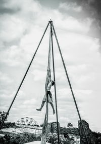 Full length of man performing stunt on rope against sky