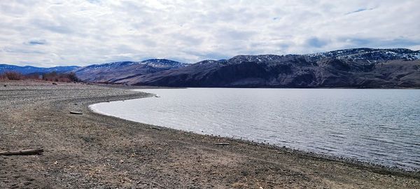 Scenic view of lake by mountains against sky