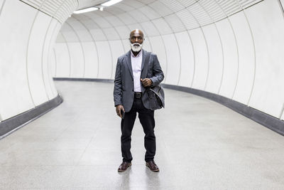 Senior commuter with laptop bag in tunnel