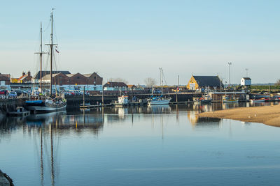 Sailboats moored at harbor against clear sky