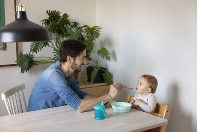 Father feeding baby at table