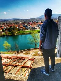 Rear view of man standing by cityscape against sky