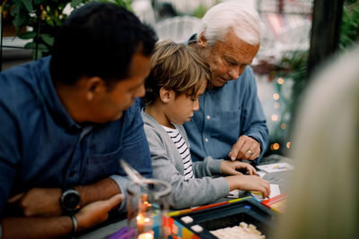 Family playing board game while sitting at table in backyard