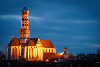 Illuminated buildings in city against sky at dusk