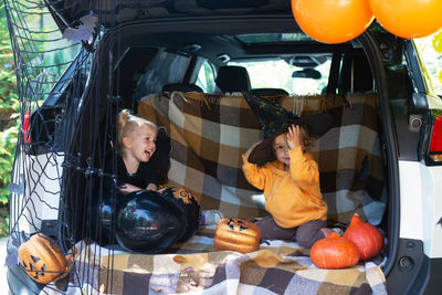 Cute sibling sitting in car trunk