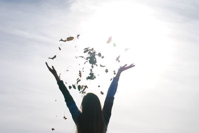 Low angle view of woman flying bird against sky