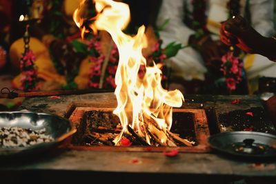 Midsection of bride and groom sitting by fire in pit during wedding