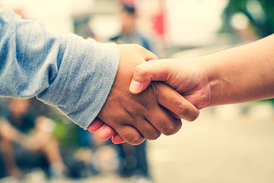 Close-up of friends holding hands outdoors