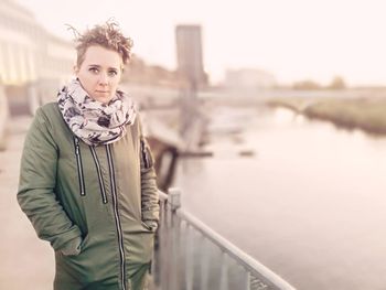 Portrait of woman wearing warm clothing while standing by river