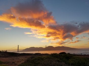 Scenic view of sea against cloudy sky during sunset