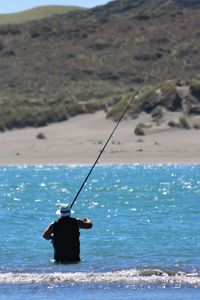 Rear view of man fishing in sea