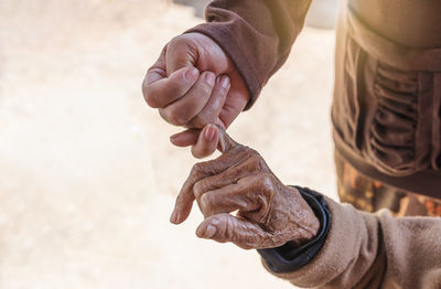 Close up of young woman holding hand of her mother, family time, hook each other's little finger. 