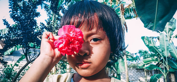 Close-up portrait of woman holding red flower