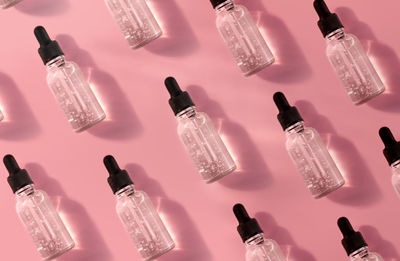 Pattern of transparent glass dropper bottle with serum on pink background. pipette with fluid acid