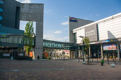 Street by modern buildings against sky in city