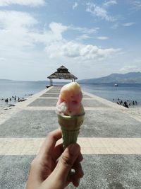 Hand holding ice cream cone at sea shore