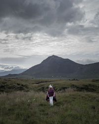 Rear view of man walking on mountain against sky