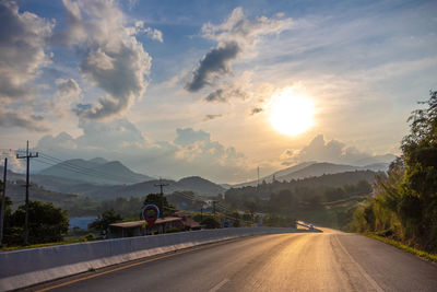 Road by city against sky during sunset