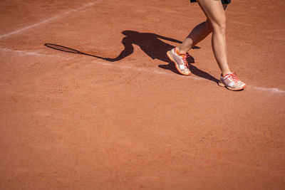 Low section of woman walking on sand