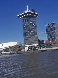 Building by sea against clear blue sky