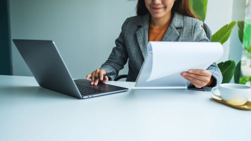 Midsection of businesswoman using laptop on table