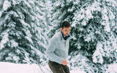 Young man standing in snow covered forest