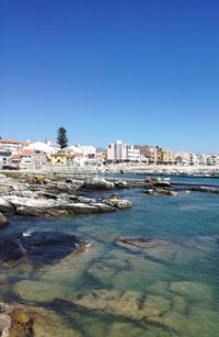 Scenic view of sea and buildings against clear blue sky