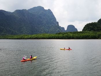 People on boat in river against sky