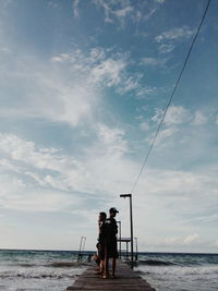 Men fishing at sea against sky