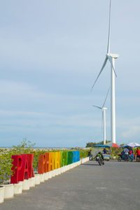 Wind turbines on road against sky