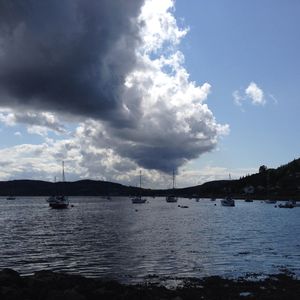 Boats in sea against cloudy sky