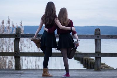 Rear view of girls at beach against sky