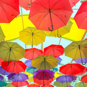 Low angle view of multi colored umbrellas hanging against sky