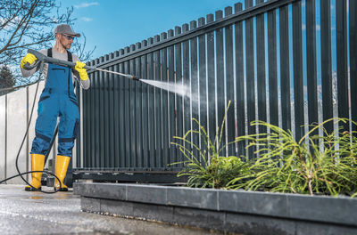 Full length of man cleaning gate