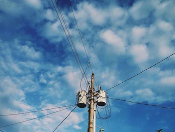 Low angle view of electricity pylon against cloudy sky