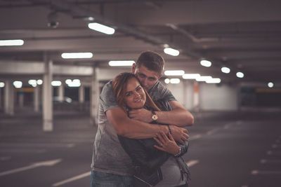 Portrait of couple embracing in parking lot