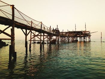 Pier over sea against clear sky during sunset