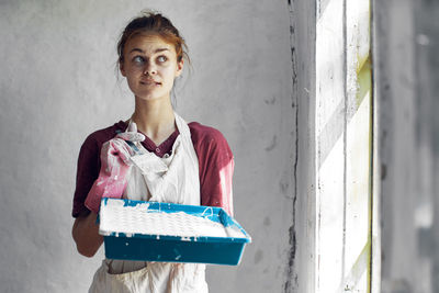 Portrait of young woman standing against wall