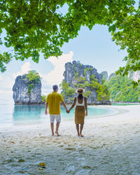 Rear view of woman standing at beach against sky