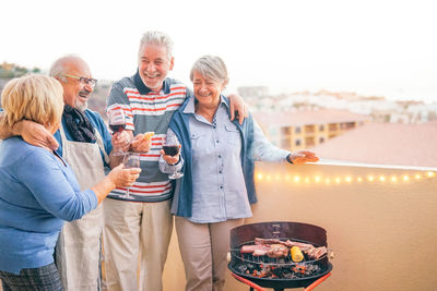 Happy senior couples enjoying wine at building terrace
