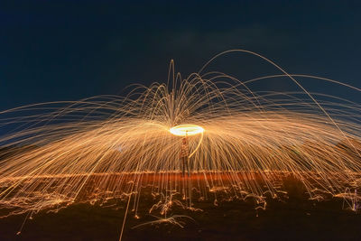 Man spinning wire wool while standing on land at night
